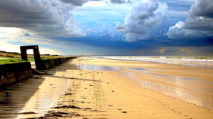 Expansive D-Day beaches at sunrise, showcasing war remnants, perfect for exploring 'combien de temps pour visiter les plag...