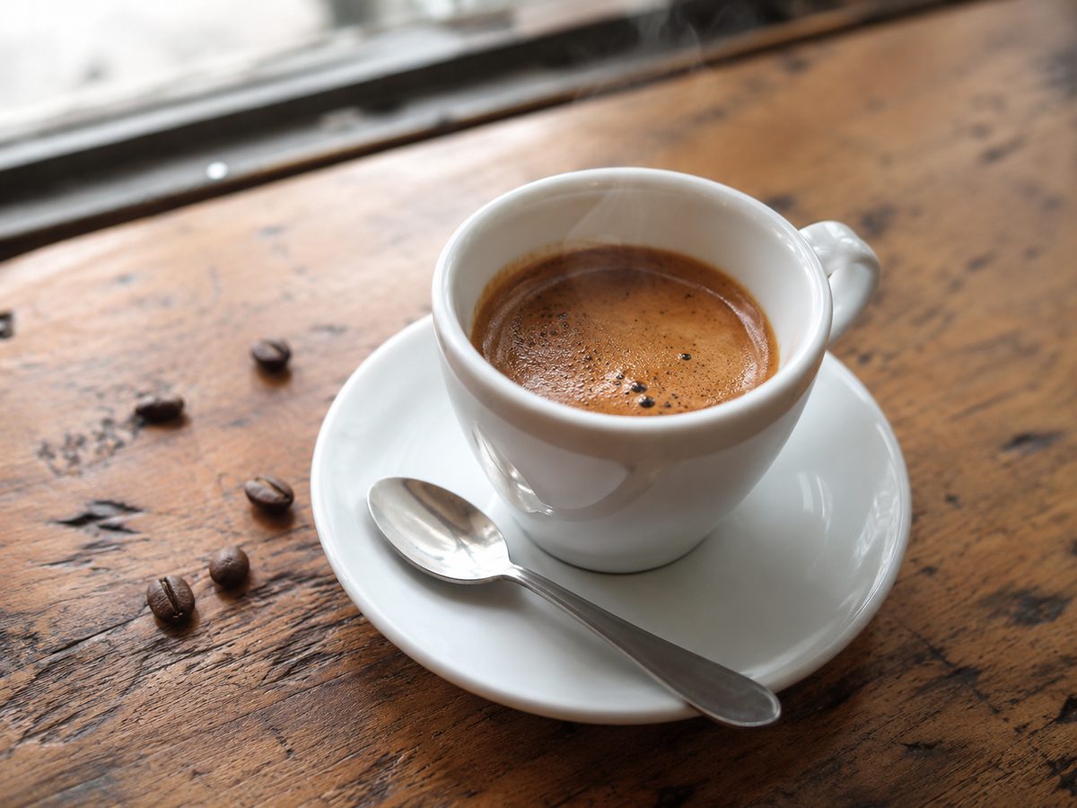 Tasse d'espresso décaféiné fumant sur une table en bois avec des grains de café torréfiés